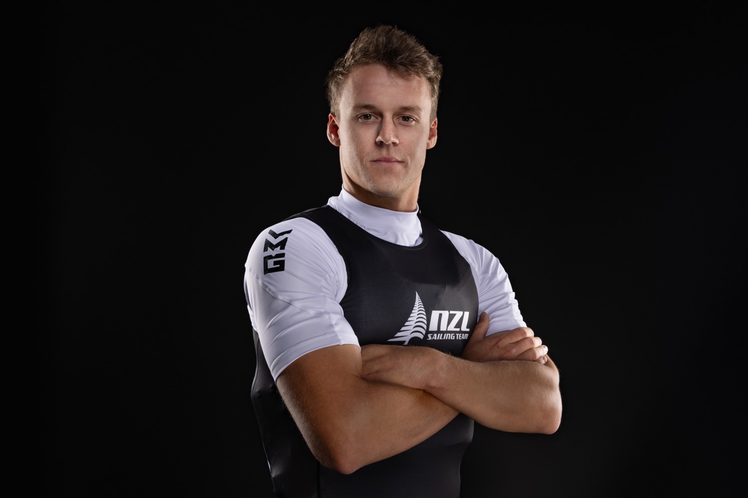 Studio portrait of a New Zealand sailing team athlete against a dark background